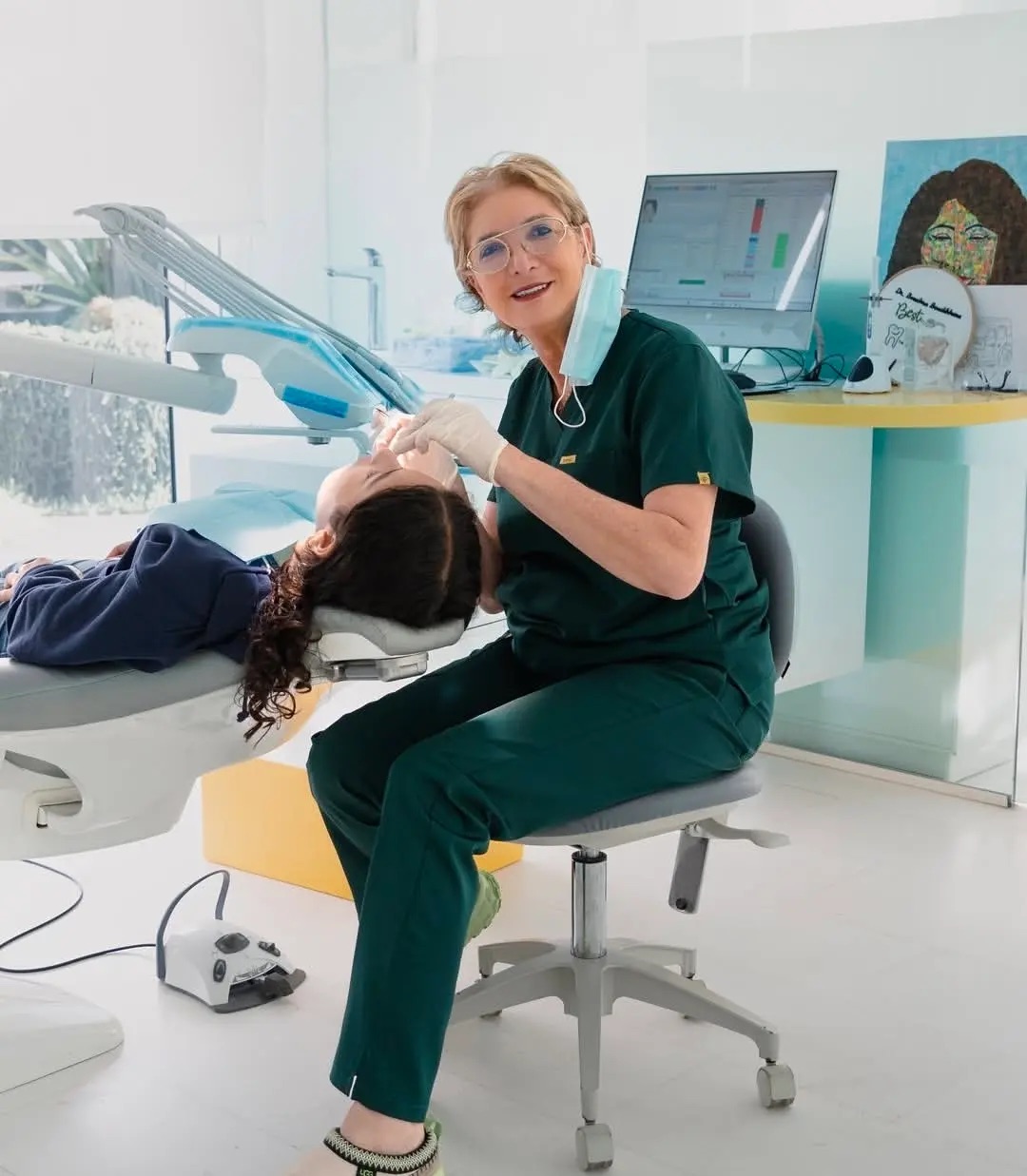 Le Dr Bouchra Bouslikhane, en tenue verte, souriante, assise au fauteuil de soins
