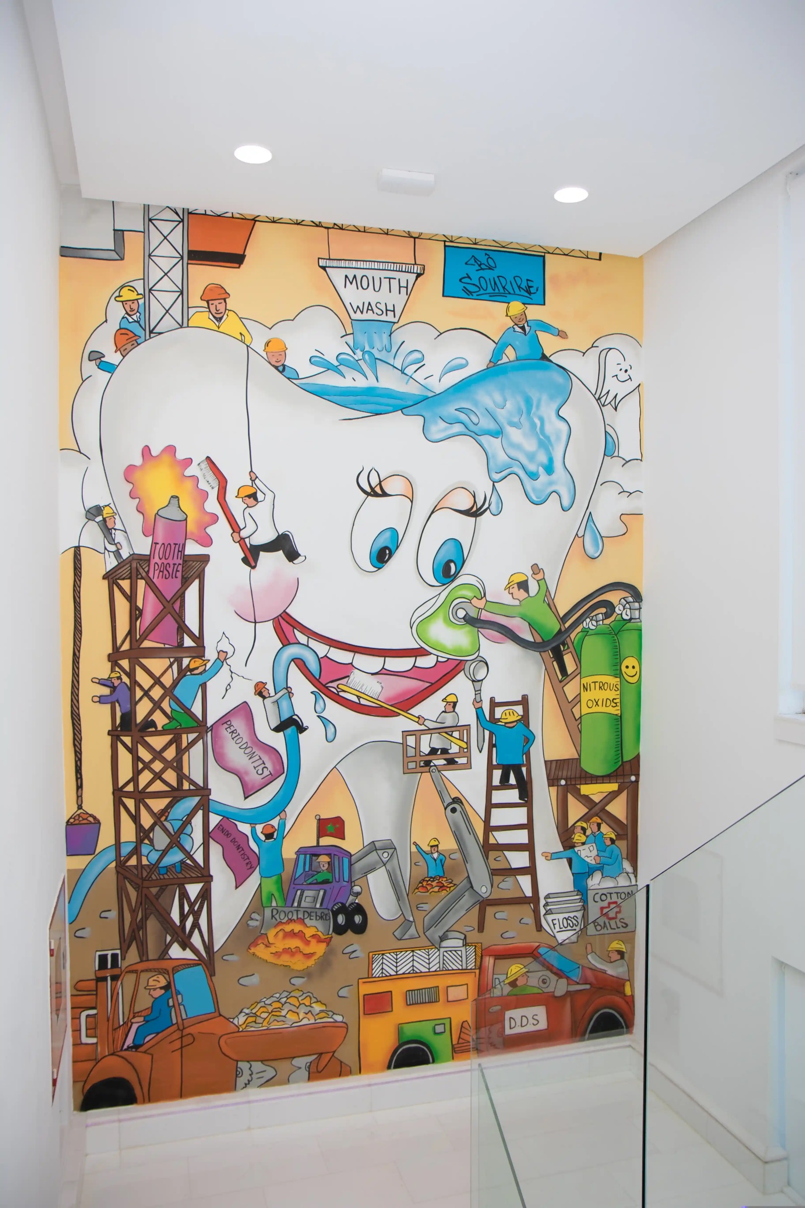Fresque murale colorée dans l'escalier : une grande dent souriante entourée d'ouvriers de chantier
